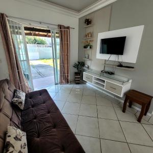 a living room with a couch and a flat screen tv at Bombinhas Brasil Residence Tourist Home no Centro de Bombinhas in Bombinhas