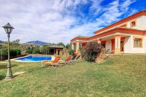 a house with a yard with chairs and a pool at 1175 villa el paraiso in Estepona