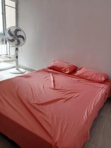 a red bed with two pillows and a fan at Apartamento en Ricaurte, Arrayanes de Peñaliza in Ricaurte