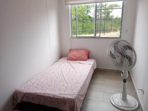 a small room with a bed and a fan at Apartamento en Ricaurte, Arrayanes de Peñaliza in Ricaurte