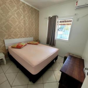 a bedroom with a bed and a window at Bombinhas Brasil Residence Tourist Home no Centro de Bombinhas in Bombinhas