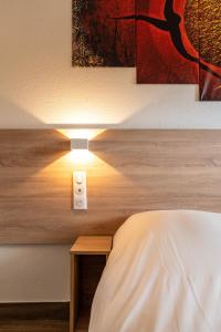 um quarto com uma cama e uma luz na parede em My KB Hôtel Montélimar em Saulce-sur-Rhône