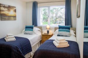 two beds in a room with blue curtains and a window at Sea Bleu in St Ives