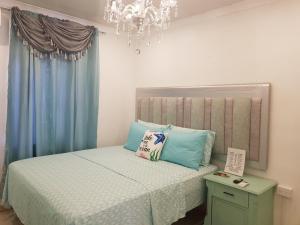 a bedroom with a bed with blue curtains and a chandelier at Jazmin's Apartment in Oranjestad