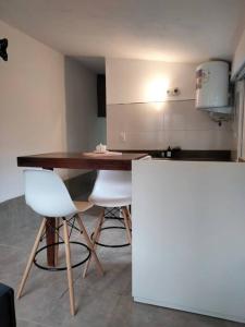 uma cozinha com uma mesa de madeira e 2 cadeiras brancas em Lodge del Plata em Potrerillos