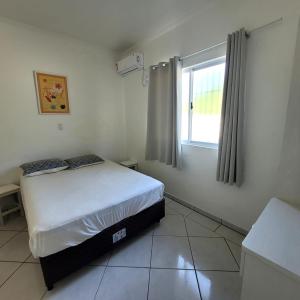 a small bedroom with a bed and a window at Bombinhas Brasil Residence Tourist Home no Centro de Bombinhas in Bombinhas