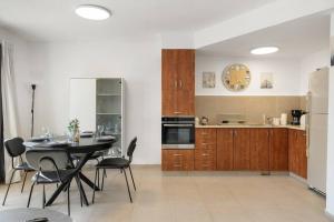 een keuken met een tafel en stoelen en een klok aan de muur bij Beautiful Ben Yehuda Apartment in Jeruzalem