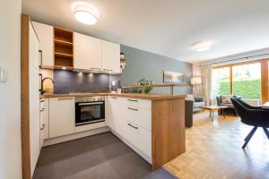 a kitchen with white cabinets and a living room at Mittendrin in Garmisch-Partenkirchen