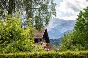 a house with mountains in the background with trees at Mittendrin in Garmisch-Partenkirchen