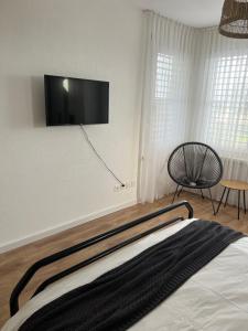 um quarto com uma cama e uma televisão de ecrã plano na parede em Black&White Apartment em Uzwil