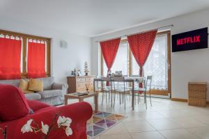 - un salon avec des rideaux rouges, une table et des chaises dans l'établissement Casa Bice, à Bormio