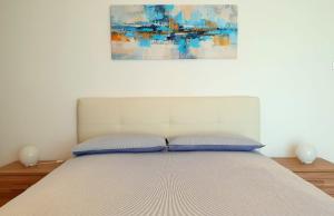 Una cama con dos almohadas y un cuadro encima. en Imma's Mansion en Casalnuovo di Napoli