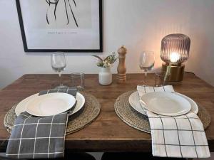 a wooden table with plates and wine glasses on it at Luminoso y acogedor apartamento in Sierra Nevada