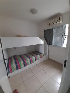 Cette petite chambre blanche comprend un lit. dans l'établissement Casa Centro Caraguatatuba, à Caraguatatuba