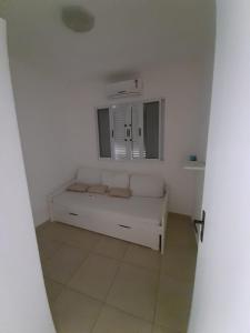 un canapé blanc dans une pièce blanche avec une fenêtre dans l'établissement Casa Centro Caraguatatuba, à Caraguatatuba 3 autres photos