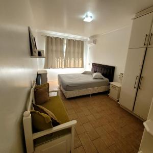 1 dormitorio con cama y sofá en Bombinhas Brasil Residence II Guest House no Centro, en Bombinhas