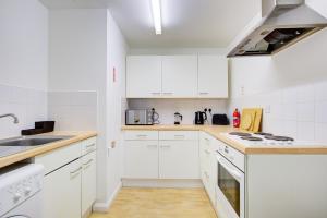 a white kitchen with white cabinets and a sink at Town Centre Apartment in Croydon