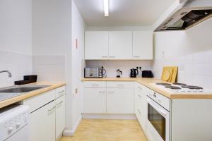 a white kitchen with white cabinets and a sink at Town Centre Apartment in Croydon