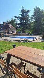 a wooden picnic table and two chairs next to a pool at Le CHALET in Pressins