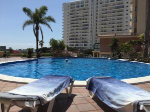 una gran piscina con 2 sillas frente a un edificio en Apartment VIParaiso, en Adeje