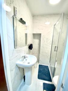een witte badkamer met een wastafel en een douche bij Stylish One bed Studio Paddington Station In Central London in Londen