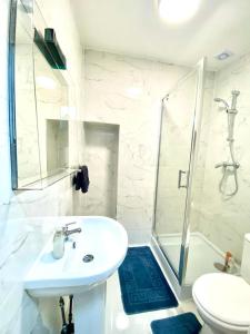 een witte badkamer met een wastafel en een douche bij Stylish One bed Studio Paddington Station In Central London in Londen