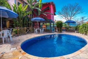 una piscina con sillas y sombrillas junto a un edificio en Pousada Recanto da Villa, en Ilhabela