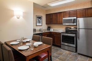 Residence Inn by Marriott Cypress Los Alamitos في لوس ألاميتوس: مطبخ مع طاولة مع كراسي وثلاجة