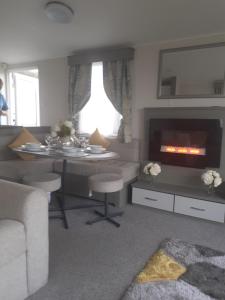 a living room with a table and a fireplace at Littlesea Haven Weymouth in Weymouth