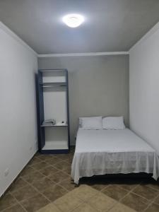 a bedroom with a bed and a small refrigerator at Hostel Anprado in Guarulhos
