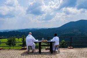 two people sitting at a table looking at the mountains at Nyungwe Nziza Ecolodge in Kitabi