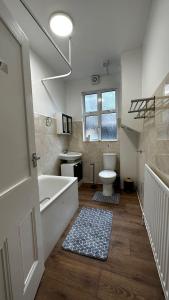 a bathroom with a tub and a toilet and a sink at Willesden Guest Room 130 in London