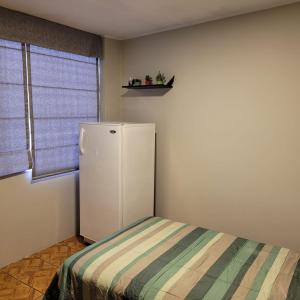 Cette chambre dispose d'une fenêtre et d'un petit réfrigérateur blanc. dans l'établissement Alojamiento Orejuelas #204, à Lima