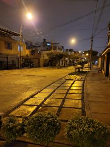 an empty street at night with lights on the sidewalk at Alojamiento Orejuelas #204 in Lima