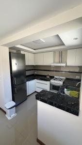 uma cozinha com armários brancos e um frigorífico de aço inoxidável em Casa en alquiler em Balcarce