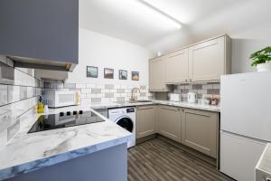a kitchen with white cabinets and a dishwasher at William Street Apartment in Cleethorpes