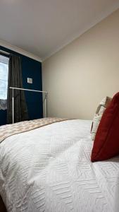 a bedroom with a large white bed with red pillows at Willesden Guest Room 130 in London