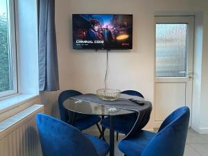 a table and chairs with a television on a wall at Charming 2-Bedrooms Apartment with a Garden at Abingdon in Oxford