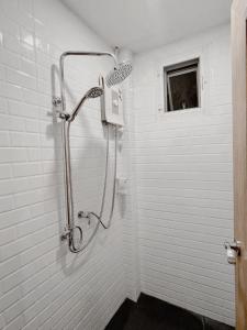 a shower in a white bathroom with a window at Nama Hostel Chiangmai in Chiang Mai