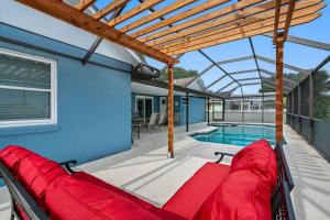 une terrasse avec un canapé rouge et une piscine dans l'établissement 13 Mins From Disney Arcade, Private Pool, Themed Rooms & HotTub, à Orlando