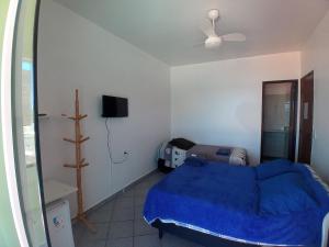 1 dormitorio con 1 cama azul y TV en Vista Mar Suítes, en Cabo Frío