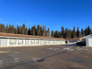 a large building with a parking lot in front of trees at Howard Johnson by Wyndham Edson in Edson