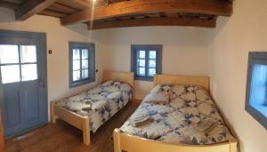 a bedroom with two beds and two windows at Casuta dintre brazi in Râșca