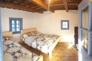 a bedroom with two beds in a room with wooden floors at Casuta dintre brazi in Râșca