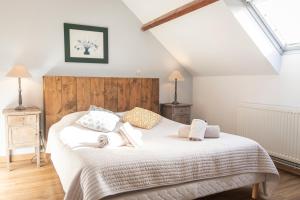 um quarto com uma cama com lençóis brancos e almofadas em La Ferme Du Grand Air em Fiennes