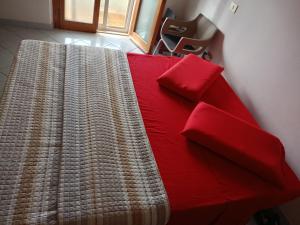 Una cama roja con dos almohadas encima. en Appartamento Santa Giusta, en Santa Giusta