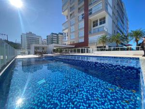 uma grande piscina azul em frente a um edifício em Apartamento com vista ampla para o mar. em Governador Celso Ramos