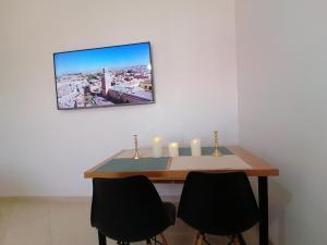 einen Esstisch mit 2 Stühlen und 2 Kerzen in der Unterkunft Light appartement in Agadir