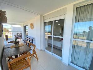 um quarto com uma mesa e uma varanda com um quarto em Apartamento com vista ampla para o mar. em Governador Celso Ramos