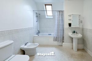 a white bathroom with a toilet and a sink at Spacious Home In Whalley Range With Free Parking in Manchester